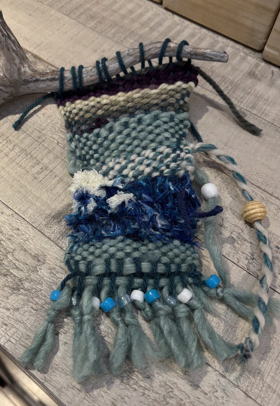 Woven wall hanging with blue and teal yarn, beads, and driftwood by Pamela Vialoux